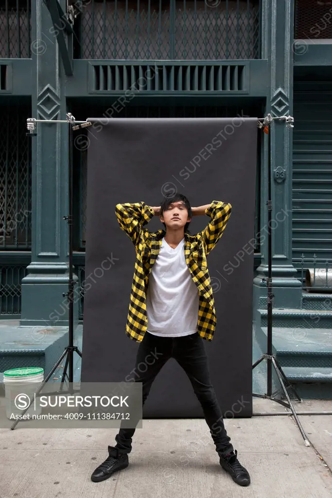 Asian man posing for photo shoot on city sidewalk