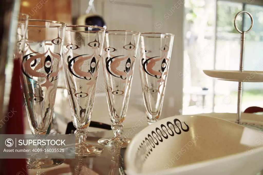 Vintage drinking glasses on glass shelf at in a house.