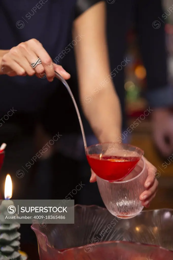 Detail of woman filling cup  from punch bowl at festive Christmas party