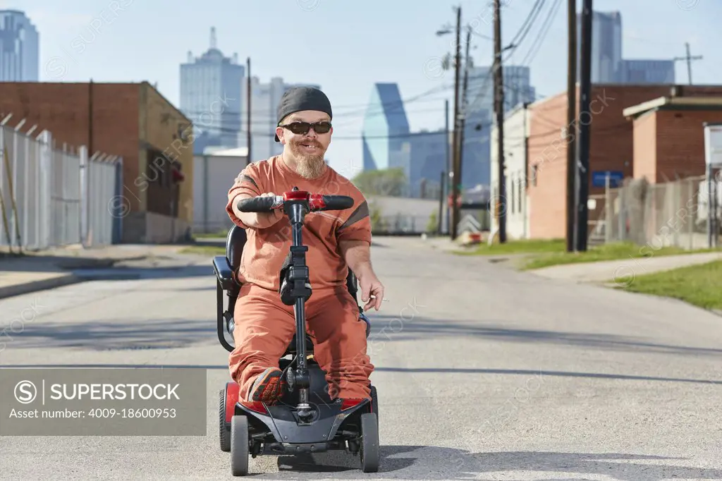 Portrait of male dwarf in the street in Texas riding a mobility scooter, smoking a cigarette