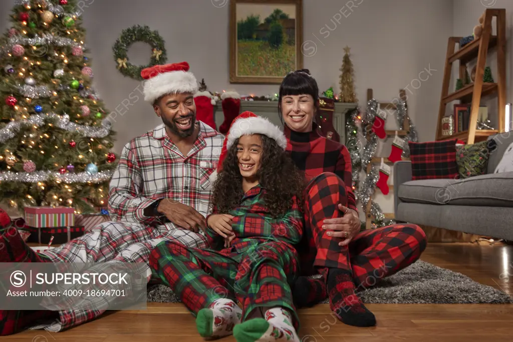 Multi-ethnic diverse family posing in front Christmas tree laughing and smiling