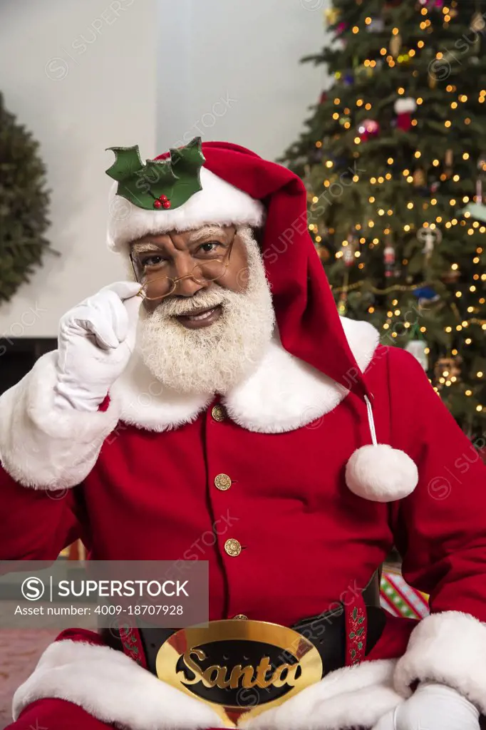 Senior Black man dressed as Santa Claus for family holiday party.