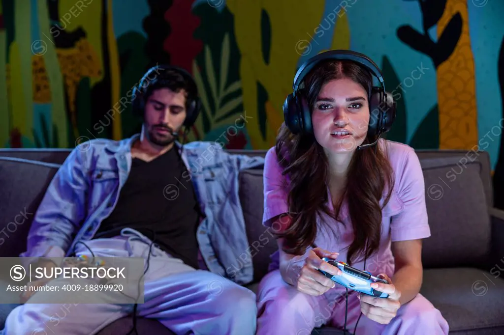 Friends playing video games at home on the couch at night