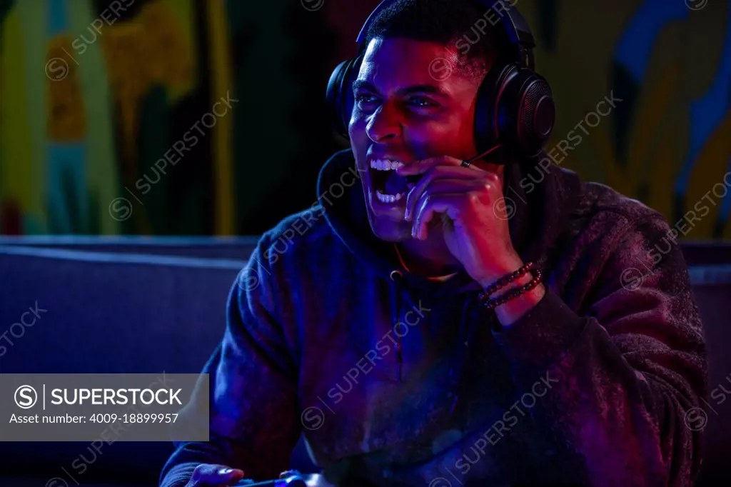 Man screaming into headset while playing video games at night.