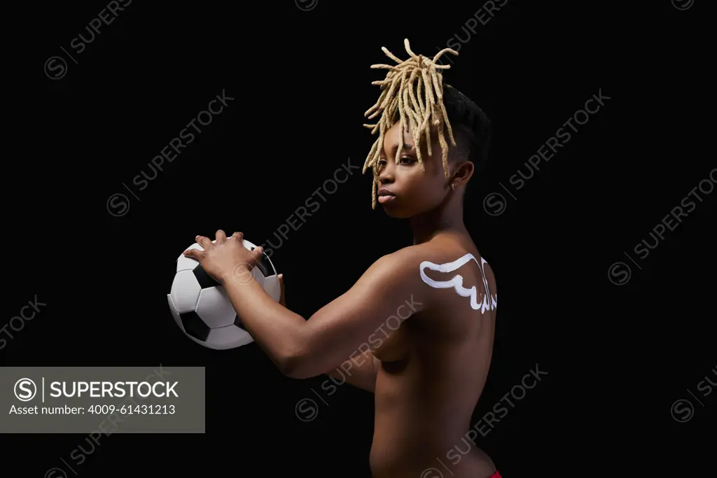 Female athlete with painted wings on her back holding a soccer ball