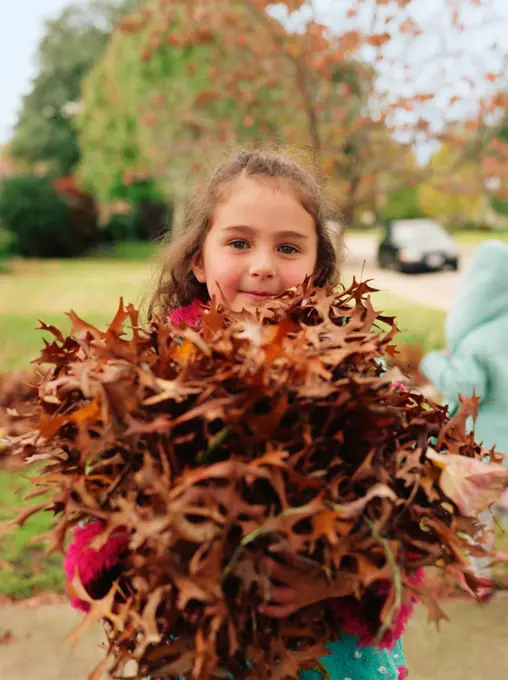 Little girls playing in the autumn leaves