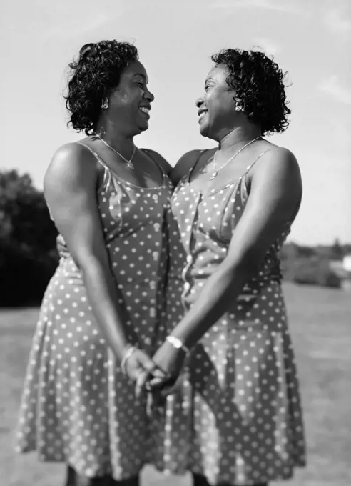 Portrait of women twins holding hands