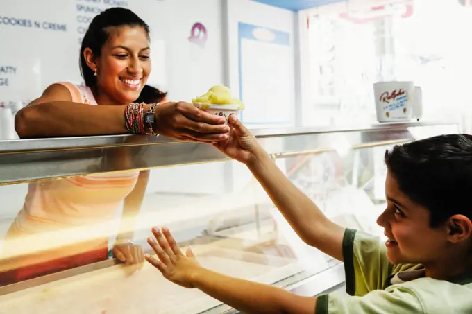 Teenage girl giving boy ice cream in shop