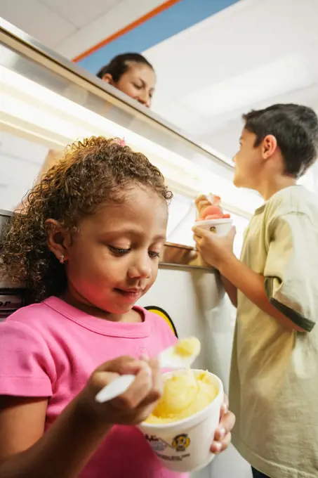 Brother and sister eating ice cream in ice cream shop