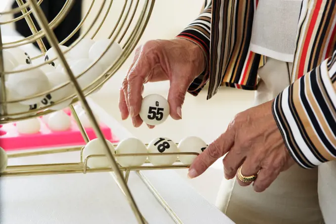 Elderly woman picking up a bingo ball