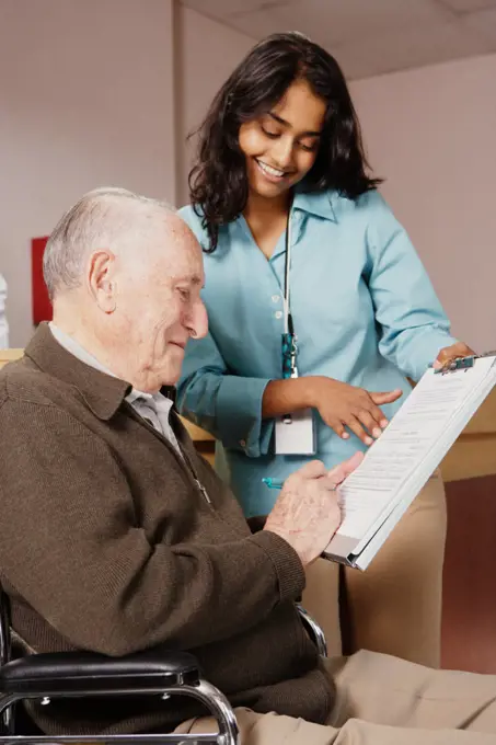 Nurse holding a form for an elderly man to sign