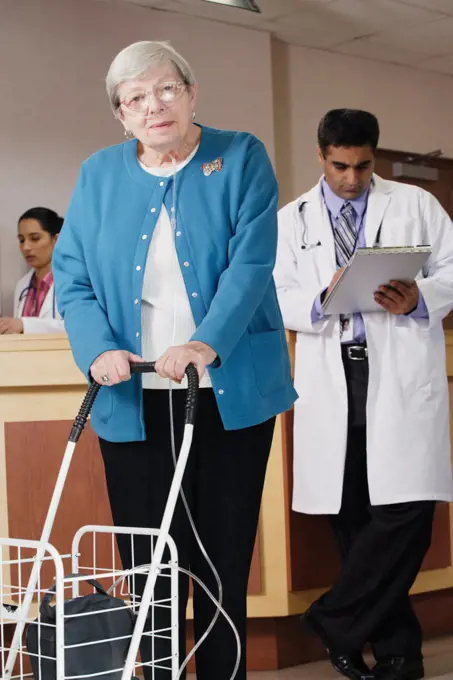 Elderly woman using a walker and a respirator