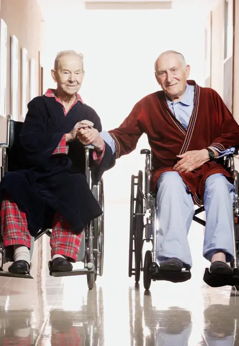 Elderly men smiling for the camera in wheelchairs