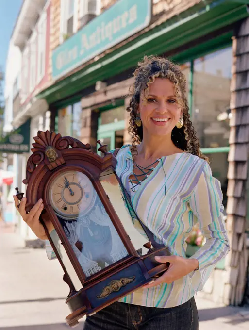 Middle-aged woman holding antique clock