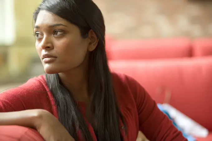 Concerned mixed race woman sitting on sofa