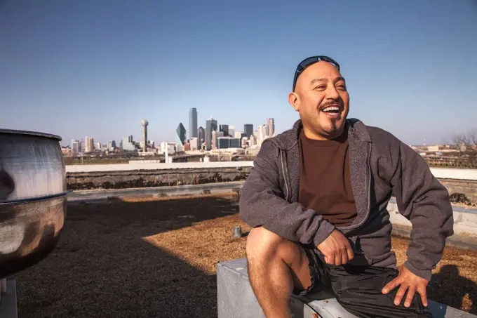 Laughing man sitting on rooftop