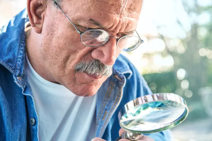 Older man using magnifying glass