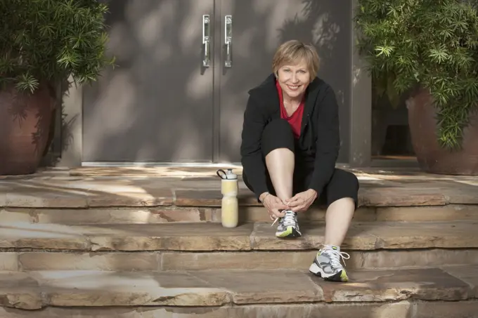 Woman tying athletic shoes before exercising