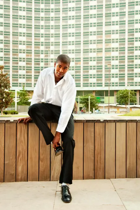 Man sitting outdoors putting on shoes