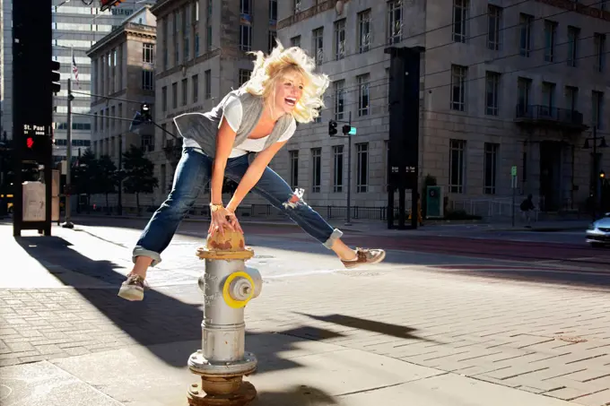 Caucasian woman jumping over fire hydrant