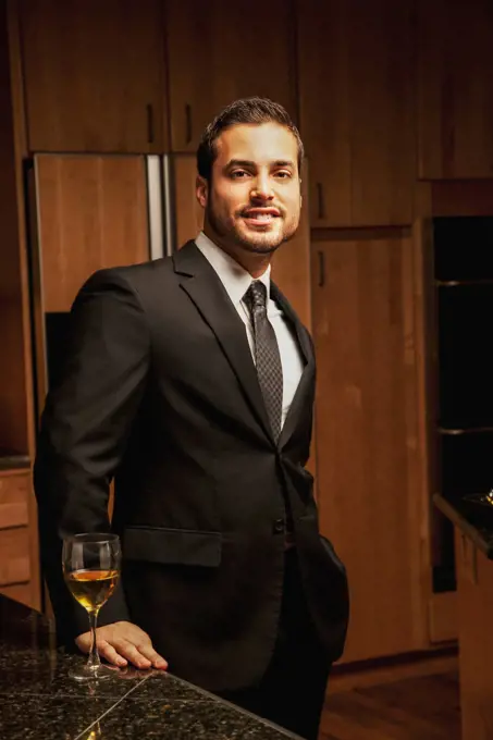 Hispanic man drinking wine in kitchen