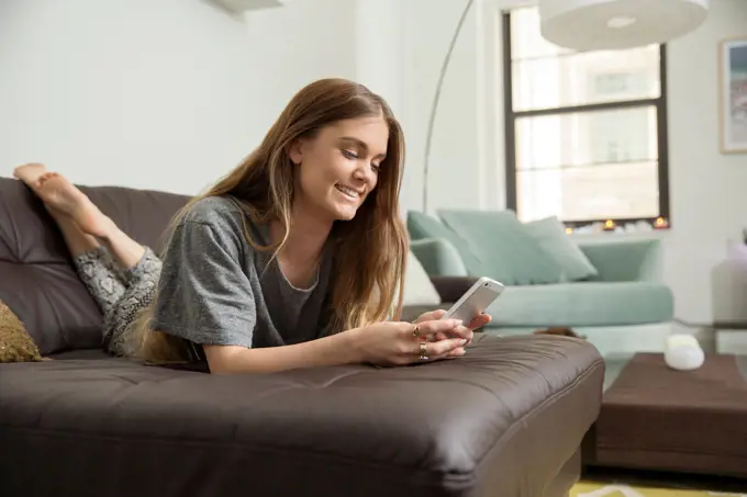 Woman using cell phone on sofa