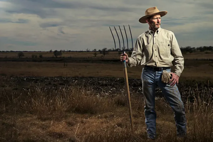 Farmer standing with pitchfork in field