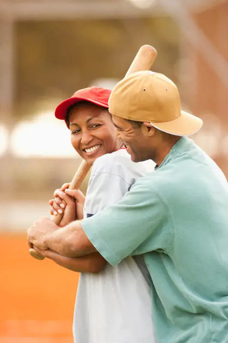 Man teaching girlfriend to play baseball