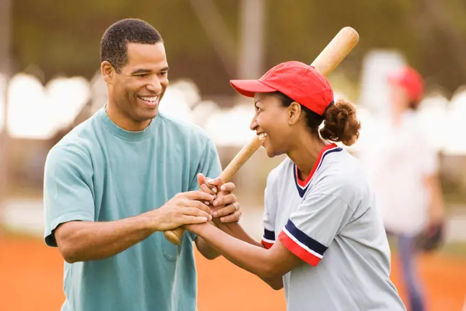 Man teaching girlfriend to play baseball