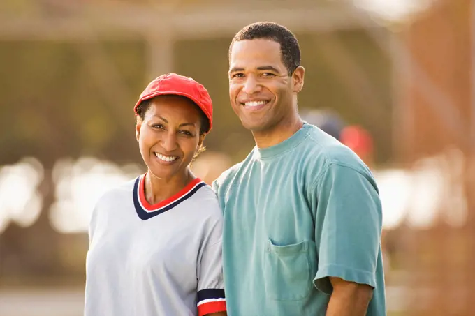 Smiling couple standing together on baseball field