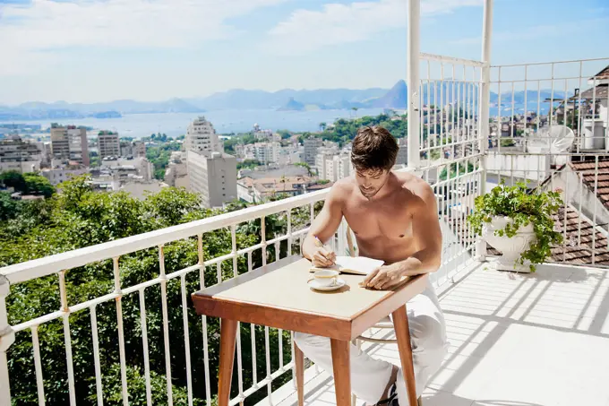 Hispanic man having coffee on urban rooftop