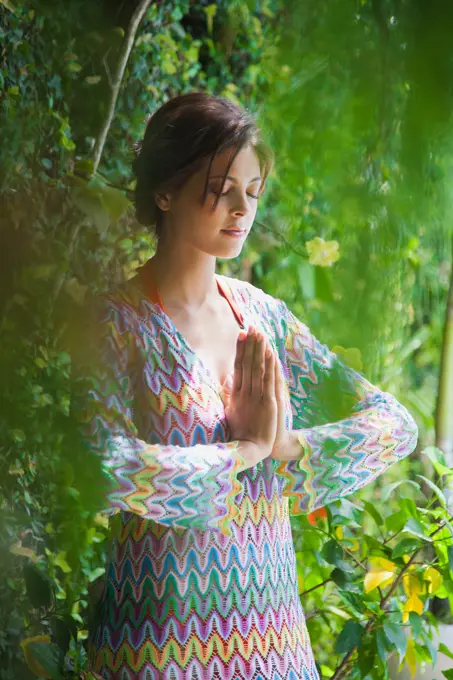 Hispanic woman meditating in garden