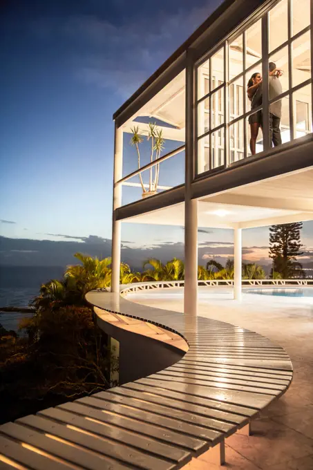 Couple hugging in illuminated modern house