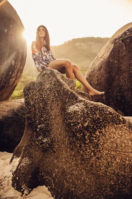 Hispanic woman sitting on boulder