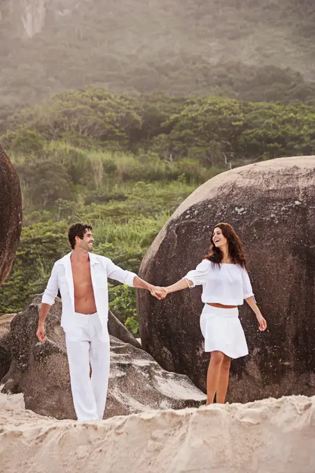 Hispanic couple in white walking on beach