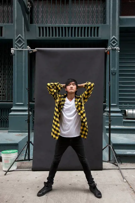 Asian man posing for photo shoot on city sidewalk