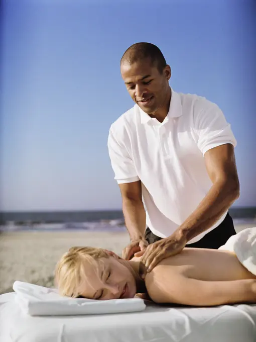 Woman receiving massage at beach