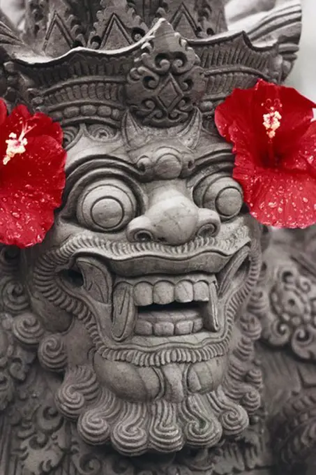 Indonesian sculpture of a lion with hibiscus flowers on both sides of the head, Bali, Indonesia