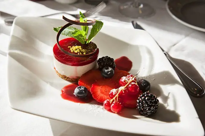 Cheesecake with chocolate and mint garnished with berries served in a plate