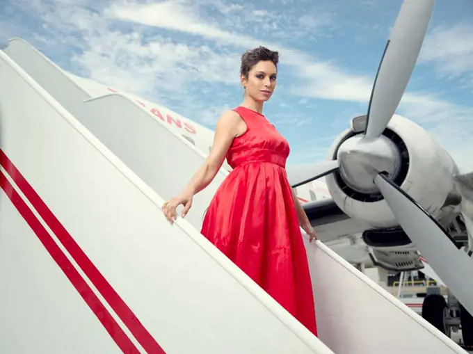 Portrait of a woman walking down the stairs of Lockheed Constellation airplane also known as "Connie" that serves as the hotel's bar at the TWA Hotel.