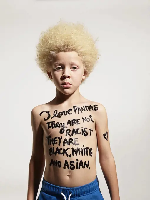 Portrait of Albino boy with words painted on body "I love pandas, They are not racist, they are black, white and Asian"