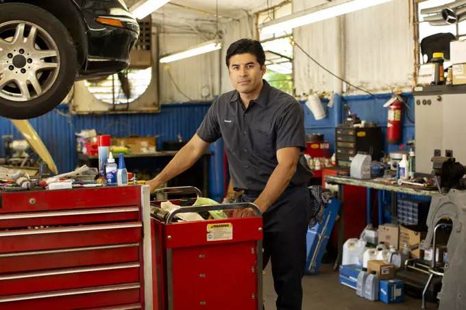 Portrait of Hispanic car mechanic working in auto shop.