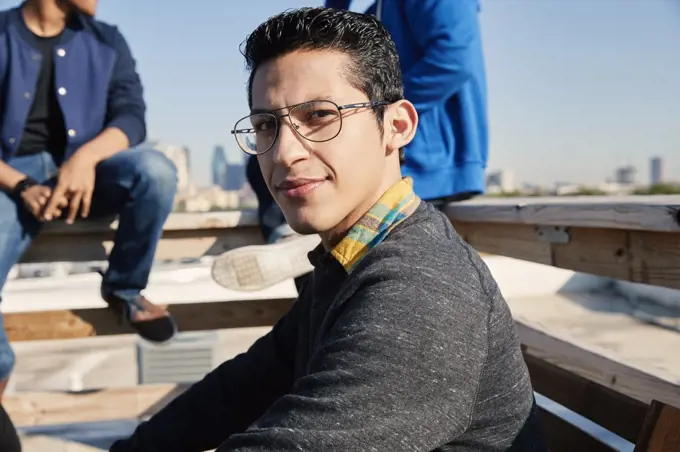 Group of young co-workers hanging out on rooftop patio Portrait of young man looking at camera 