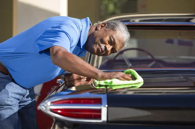 Older man drying off 1960 Oldsmobile Super 88 Holiday Sport Sedan after detailing 