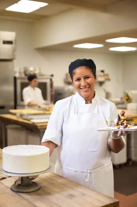 Portrait of female baker smiling in kitchen preparing to decorate cake