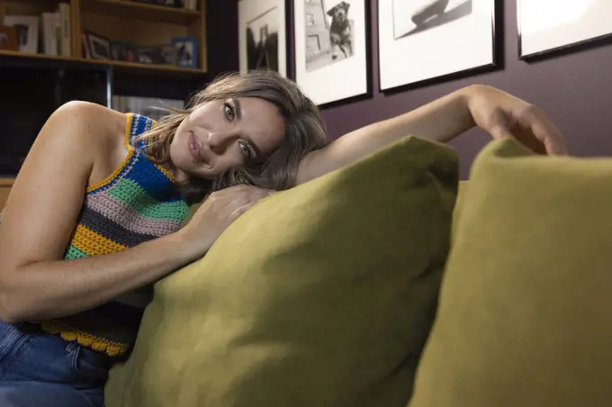 Portrait of casually dressed caucasian woman lounging on couch in home library 