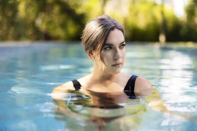 Portrait or caucasian woman floating in swimming pool in backyard 