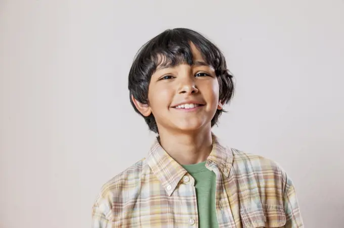 Portrait of a Mixed Race boy looking into camera with a toothy smile. 