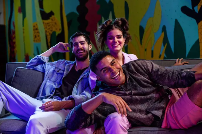 Group of friends sitting on couch watching tv at night. 