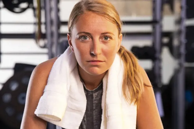 Portrait of a woman with a towel around neck looking into camera after workout. 